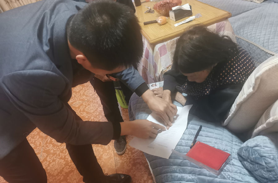 工作人员指导老人签字盖手印.png